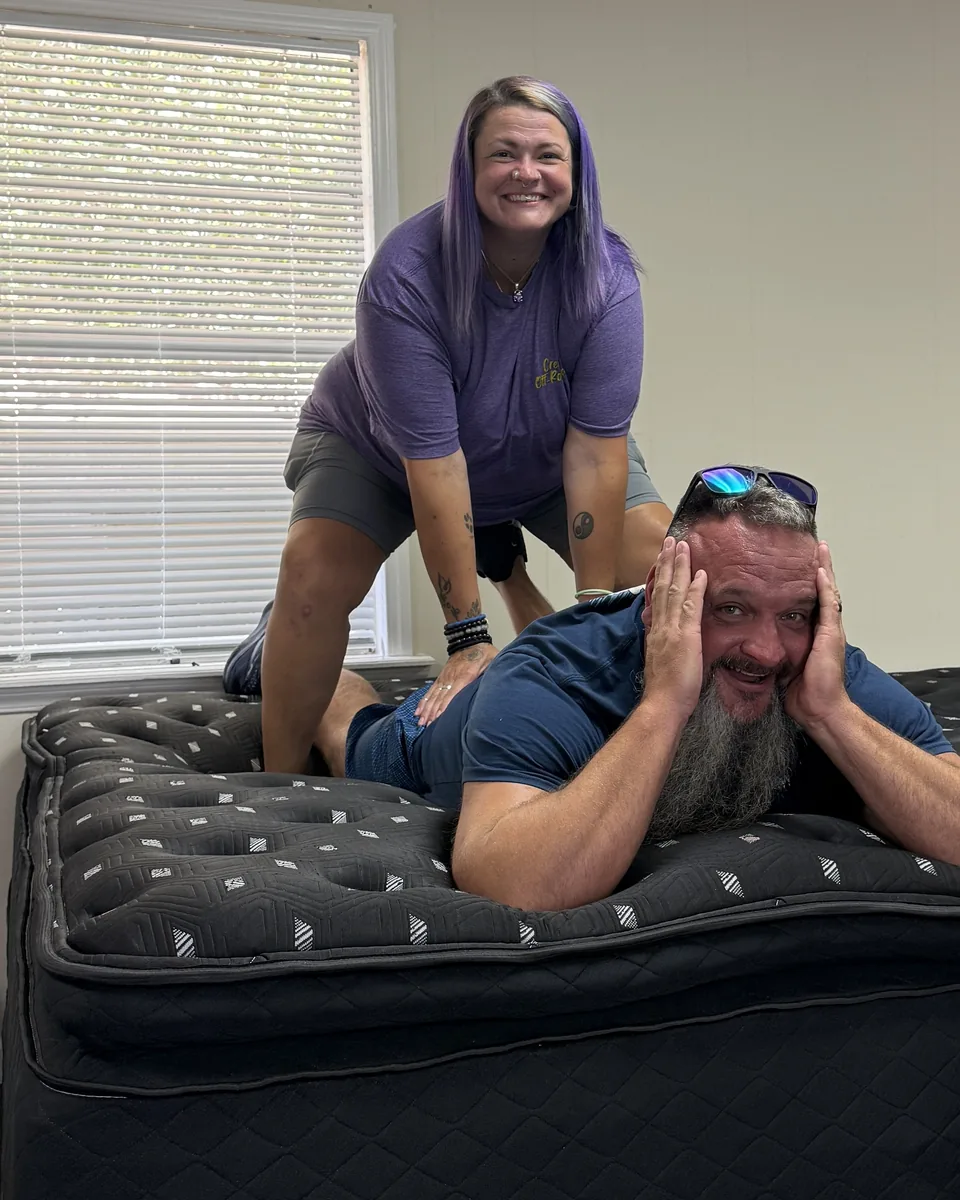 Customers laughing while trying a mattress